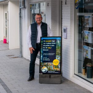 EDC medarbejder, der står med digitalt A-skilt foran EDC-butikken